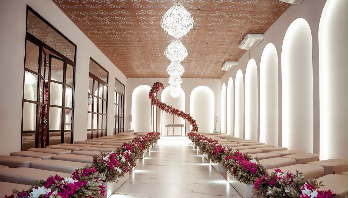 Salão da Casa Helenya com lustres e flores ao longo do corredor